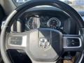 Steering wheel and dashboard of a 2011 RAM 1500 with gauges and controls visible in the foreground