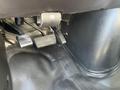 Close-up of the footwell in a 2013 Chevrolet Express showing the accelerator brake and clutch pedals along with the rubber floor mat