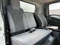 Interior of a 2016 Isuzu NQR showing two front seats and a bench seat with gray fabric upholstery