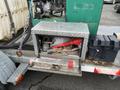 A dual flat deck trailer with a storage compartment open revealing various tools and equipment including a red funnel and a toolbox inside