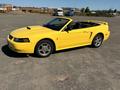 A yellow 2003 Ford Mustang convertible with a sporty design and a sleek body style, featuring a black interior and chrome wheels