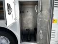 An open metal storage compartment of a 2009 Morgan Olson Workhorse with a jack and a dark compartment inside