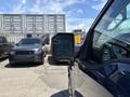 A 2015 Ford F-150 with a side mirror visible in the foreground parked next to other vehicles in a lot