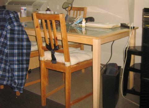 A glass dining room table with wooden legs and a simple design accompanied by a wooden chair with a cushion