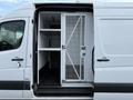 A 2012 Mercedes-Benz Sprinter van with an open side door revealing a metal partition and shelves inside