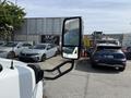A 2020 Chevrolet Express van with a side mirror in focus showing part of a parking lot with other vehicles in the background