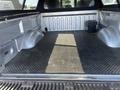 A 2014 Ford F-150 truck bed with a textured rubber mat and secured tool box in one corner