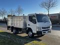 A 2014 Mitsubishi Fuso FE truck with a flatbed and metal sides parked on a street