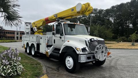 A white 2006 International 7500 truck equipped with a yellow aerial lift and a utility bed for maintenance and repair work