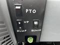 Control panel of a 2013 Ford F-650 featuring switches labeled PTO, UP, DUMP, and BEACON with a green connector below