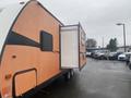 A 2015 Winnebago of Indiana Travel Trailer with an orange exterior and a slide-out room extended from the side