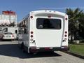 A white 2014 Chevrolet Express bus with a large rear window and red taillights parked in a lot