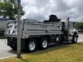 2017 International WorkStar 7600 dump truck with a silver body and black accents positioned at a slight angle showing its rear and side view