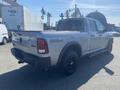 A silver 2021 RAM 1500 Warlock pickup truck with black wheels and a crew cab design parked at a loading area