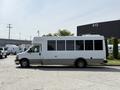 A white 2020 Chevrolet Express shuttle bus with large windows and a sleek design parked on a concrete surface