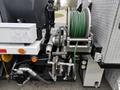 A 2016 Peterbilt 348 with a hose reel and hydraulic components visible including a green hose and various valves and fittings