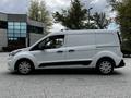 A 2019 Ford Transit Connect van in white with black accents parked on a paved surface showcasing its profile and distinctive design features
