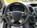 The interior view of a 2015 Ford Transit highlighting the steering wheel with Ford logo controls and dashboard displays
