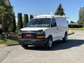 A white 2019 GMC Savana van with a black front grille and roof racks parked on a driveway