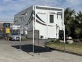 A 2018 Westland Travelaire camper mounted on adjustable legs with a white exterior and decorative graphics on the side