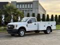 A 2018 Ford F-350 pickup truck in white with a utility bed and black wheels parked at an angle