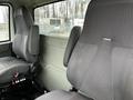 The interior of a 2013 International DuraStar showing two gray upholstered seats with a simple design and controls on the floor near the driver's side seat