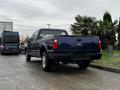 A blue 2008 Ford F-250 Super Duty truck parked with its rear facing the viewer showcasing its chrome bumper and bed design