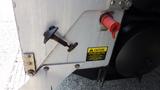 A close-up of a 2003 International 5600i with a caution label and a red cap on a valve beside a lever handle attached to the truck's side