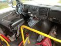 Interior of a 2012 Chevrolet Express showing the driver's seat dashboard and controls with visible gear shift and a yellow barrier partition