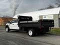 A 2021 Ford F-550 with a flatbed truck design featuring a black dump bed and white cab parked on a street