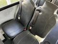 Two black leather seats with safety belts in a vehicle interior