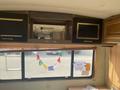 Interior view of a 1987 Chevrolet Fleetwood Pace Arrow featuring cabinetry, windows, and decorative flags hanging along the wall
