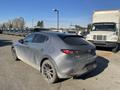 A silver 2023 Mazda MAZDA3 with a dirty exterior parked at an industrial location