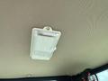 Interior ceiling light fixture inside a mini excavator with a textured cover and a visible mounting screw