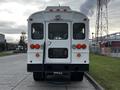 A 2013 International 4200 bus viewed from the rear with red tail lights and a door on the back