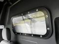 A clear window with metal screws framed in black, showing part of a 2020 Ford Transit interior