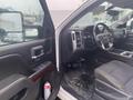 Interior of a 2015 GMC Sierra 1500 showing the driver's seat steering wheel and dashboard with several controls and a can of spray cleaner on the floor