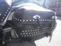 A black leather saddlebag with metal studs attached to a 2009 Harley-Davidson Flstc motorcycle