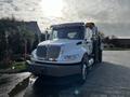 A white 2013 International DuraStar 4300 truck with a chrome grille and orange lights on top is parked facing forward