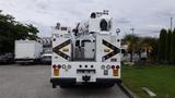 A white 2012 International 7400 truck with a raised bucket and utility equipment on the rear, featuring multiple lights and reflective safety markings