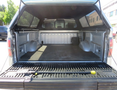 Interior of a 2014 Ford F-150 truck bed showing the cargo area with a rubber mat and side storage compartments