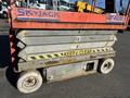 A 2010 SkyJack SJ4626 scissor lift with a red and gray color scheme showing signs of wear and rust on the metal plates and wheels