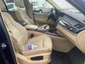 Interior of a 2009 BMW X5 featuring beige leather seats a center console and a water bottle on the passenger seat