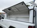 A white 2022 GMC Sierra 1500 truck with an open truck bed cover revealing a spacious empty interior with shelves inside