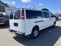 A white 2012 Chevrolet Express van with tinted windows parked in a lot showing its rear and side profile