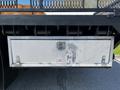 A metal storage box mounted on the back of a 2012 Freightliner M2 112 with a latch and a logo on the side