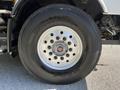 A close-up view of a large truck wheel with a shiny silver rim and a black Bridgestone tire showing several lug nut holes