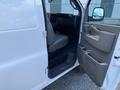 A 2023 GMC Savana with an open driver's side door showing the interior featuring a gray seat and dashboard details