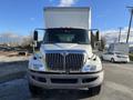 A 2013 International 4300 truck with a large white cargo box and chrome accents is seen from the front with a clear view of the grille and headlights