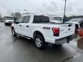 A white 2016 Ford F-150 FX4 pickup truck with chrome wheels and a crew cab parked in a lot